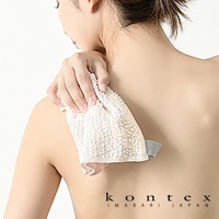 女性手持一件白色紋理的天然素材按摩洗澡巾，巾面帶有細緻的顆粒感，邊緣有灰色織帶，展示其柔軟質地。