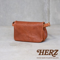 職人手作皮革Organ斜背包，採用柔軟的棕色皮革製成，包身呈現自然的皺褶感，並配有可調節的皮帶和金色金屬扣環。