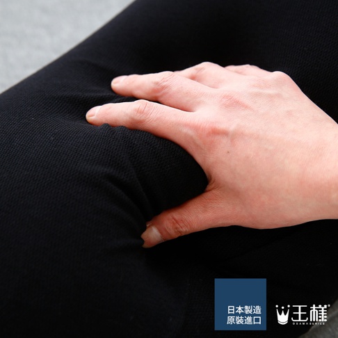 黑色抱枕，表面為織物材質，有細密的紋理。一隻手按壓在抱枕上，展現其柔軟的觸感。