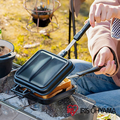 黑色直火專用熱壓三明治夾烤盤，兩片烤盤可分離，具有黑色防滑手柄，烤盤內有兩份吐司。