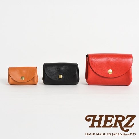 三款職人手作皮革零錢包，依序為淺棕色、黑色、紅色，皆為簡約設計，附有金色按扣，展示於白色背景。
