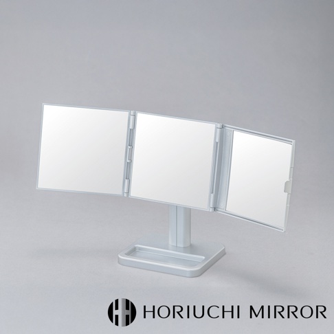 銀色金屬材質的 NAPURE 桌上型三折化妝鏡，擁有三面鏡面，可360度旋轉，鏡架呈簡潔的立體造型，底座為方形托盤設計。