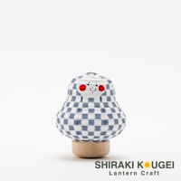 達摩不倒翁造型提燈，白色紙質燈身印有藍色細格紋，臉部有兩顆紅色圓點和微笑表情，底部為木製圓形座。