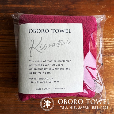 包裝內的深粉紅色細纖浴巾，標籤寫有「OBORO TOWEL KIWAMI」，並註明「MADE IN JAPAN / COTTON 100%」。