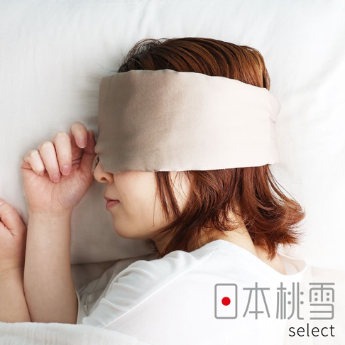 一位女性側身躺在枕頭上睡覺，配戴著一款色澤柔和的絲綢材質眼罩，眼罩寬度覆蓋了雙眼至額頭位置。圖片右下角標註有 hiorie select 的品牌字樣，整體呈現出簡約、舒適的睡眠情境。
