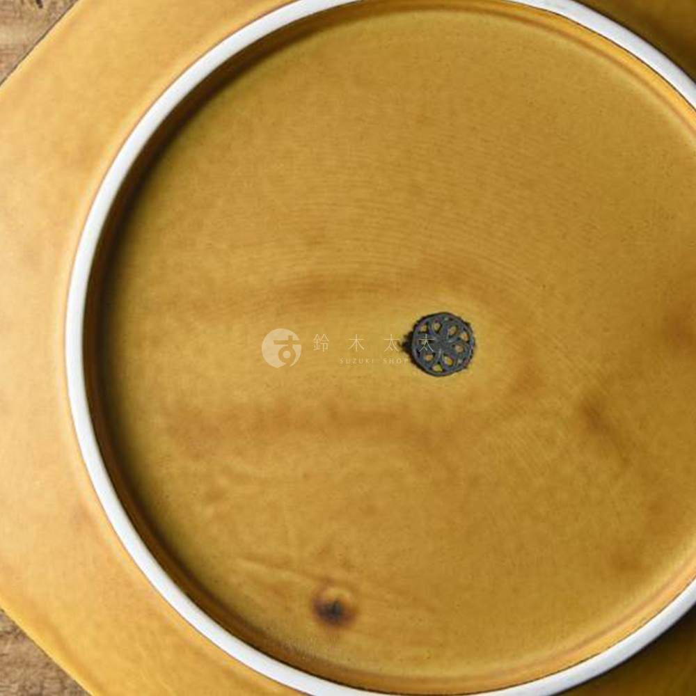 芥黃釉美濃燒八角盤，釉色呈現溫潤的芥末黃，盤緣帶有細緻的白色釉邊。盤底中央有品牌標誌，為一個黑色鏤空圓形圖案，下方印有「SUZUKI SHOP」字樣。