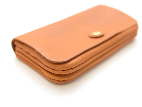 職人手作皮革旅行用長夾，呈現自然棕色皮革，設有金屬按扣，多層次結構，設計簡約。