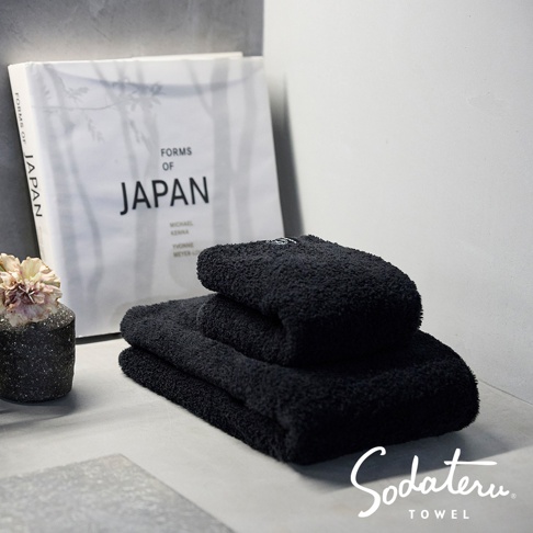 一疊黑色毛巾，旁邊有一個裝飾用的花瓶和一本名為 FORMS OF JAPAN 的書籍。