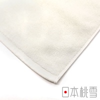淺米色毛巾，表面有細緻的絨毛紋理，邊緣有整齊的縫線，角落處印有「日本桃雪」字樣。