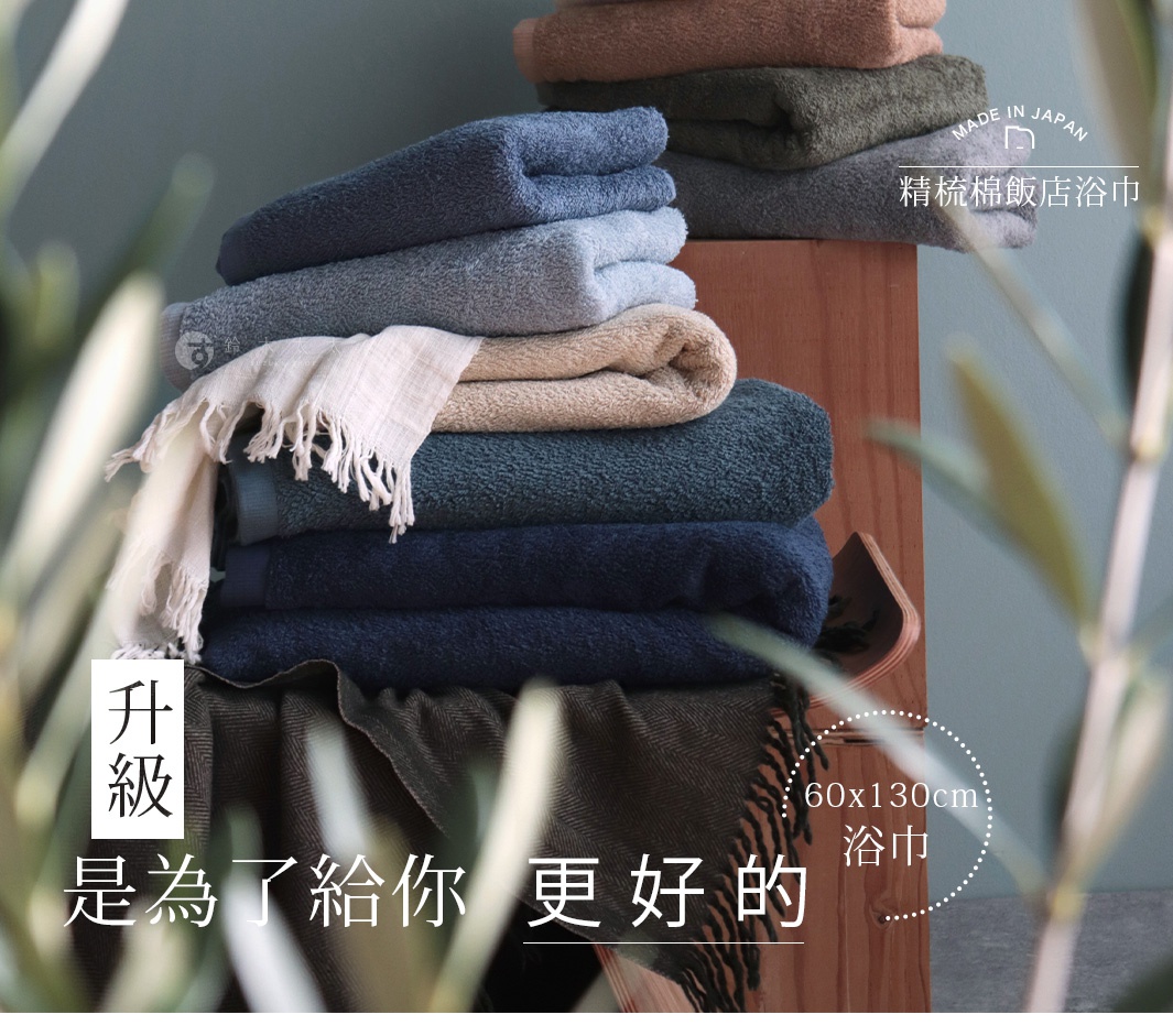 堆疊的精梳棉飯店浴巾，顏色包含海軍藍、深綠、淺藍、灰色、駝色和白色，部分浴巾帶有流蘇。