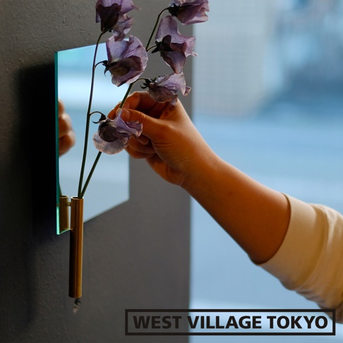 壁掛式帶有鏡面效果的漂浮花器，黃銅材質，可容納一至兩枝淺紫色花朵。