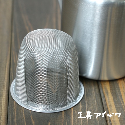 一個不鏽鋼霧面直筒茶壺，配有一個銀色網狀茶濾，放在木質桌面上。