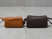 兩款職人手作皮革Organ輕巧拉鍊單肩包，一款為淺棕色，另一款為深棕色，皆為拉鍊式開合，搭配金屬拉鍊及肩帶扣環。