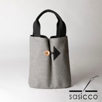 直式收納托特包，採用灰白色系的細小棋盤格紋刺子織布料，搭配黑色提把。包身中央以黑色箭頭形狀布片，搭配一顆木質鈕扣作為裝飾。