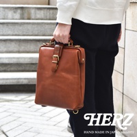 職人手作皮革迷你軟皮杜勒斯包，採用棕色鞣革皮革，設有頂部提把、可調節帶扣開合及金色五金配件。