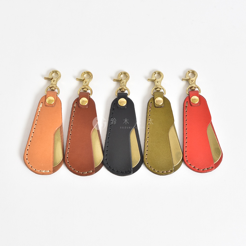 五款職人手作皮革隨身金屬鞋拔，顏色分別為淺棕、深棕、黑色、軍綠及紅色，皆附有黃銅色掛鉤。