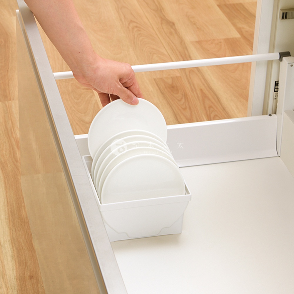 一人手持白色餐盤，將其放入白色收納架中，收納架內已有數個白色餐盤堆疊。