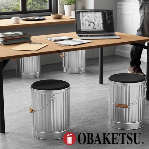 OBAKETSU 手工製作的銀色儲物凳，帶有木製手柄和黑色坐墊，擺放在現代辦公桌下方。