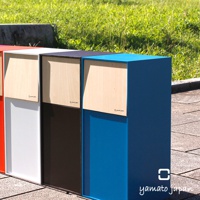 四個純手工木製前開式迷你垃圾桶，顏色分別為紅色、白色、深棕色和藍色，皆有木紋前蓋，擺放在戶外石板路上。