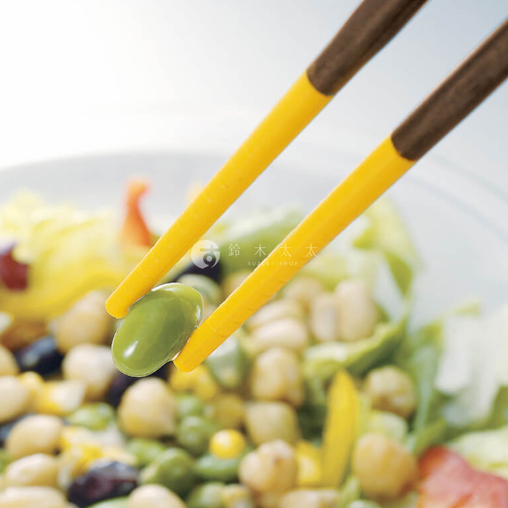 一雙黃色和棕色的筷子夾著一顆綠色的豆子，上方有日文和英文的品牌標誌。
