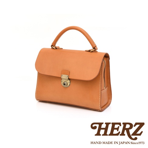 日本HERZ手提包，淺棕色皮革製作，帶有金色鎖扣與拉鍊，簡約經典設計。