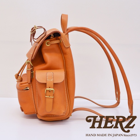 職人手作皮革復古風旅行後背包，以天然皮革製成，呈現溫潤的焦糖棕色。包款設計有束口、翻蓋、金屬釦及拉鍊外袋，搭配兩條可調節的皮革肩帶，整體風格簡約耐看。