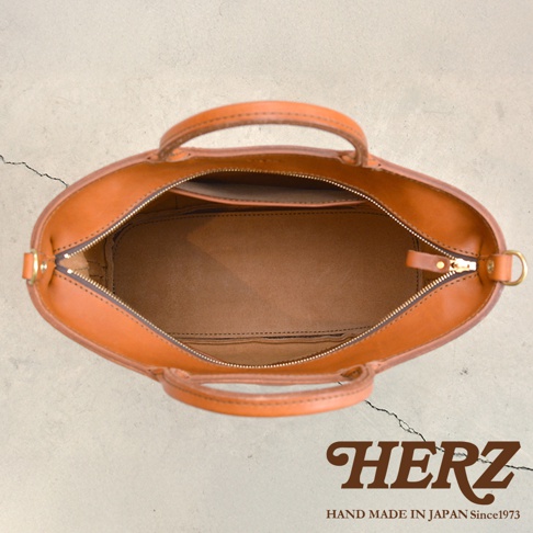HERZ 職人手作皮革 Organ 兩用拉鍊托特包，從上方視角展示包包內部，駝色皮革材質，附有雙提把及拉鍊開口。