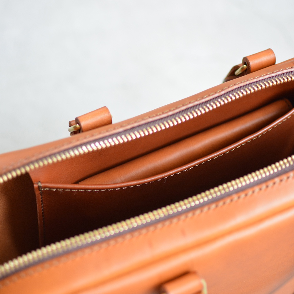 職人手作皮革Organ商務公事包 G-40，展現皮革內袋與金色拉鍊細節，溫暖的棕色調，強調精緻工藝。