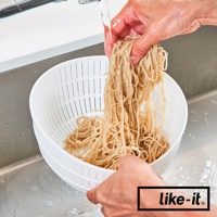 白色雙層瀝水籃，上方裝有麵條，正被水沖洗。