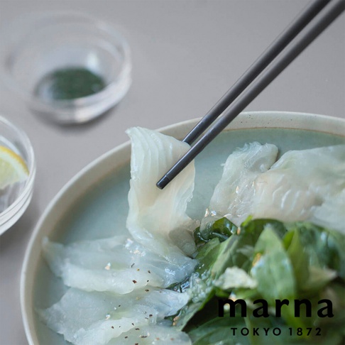 marna TOKYO 1872 標誌下，夾子夾著一片生魚片，旁邊有其他生魚片和綠葉，背景有小碗和檸檬片