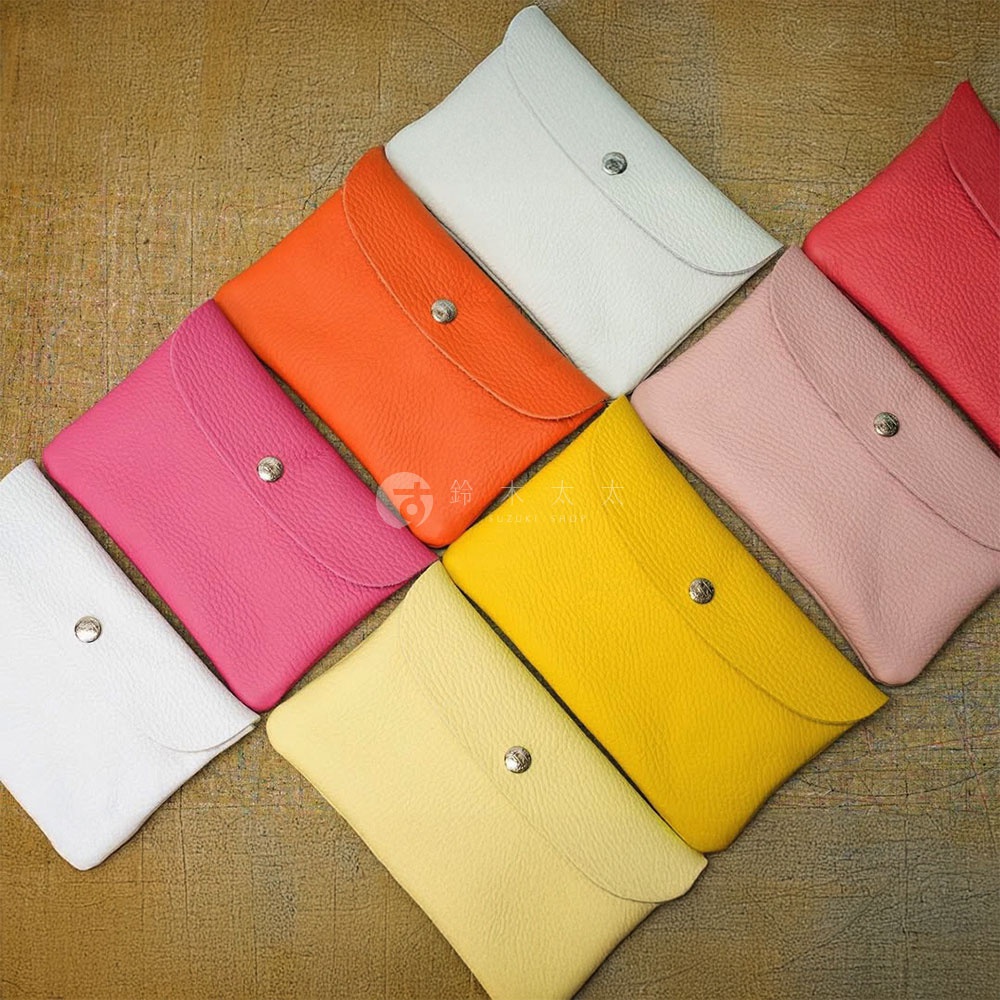 多個京都職人手作多功能收納包，顏色包含：亮紅、粉紅、橘色、黃色、淡粉色、米白色。材質為皮革，設計簡潔，帶有金屬按扣。