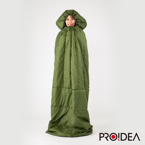 一件綠色、填充飽滿的兩用睡袋，具有連帽設計，從頭部到腳部完全包裹住一位女性。睡袋採用絎縫填充，材質看起來是光滑的防潑水布料。