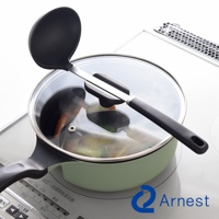 Arnest 鴛鴦鍋上放著湯勺，湯勺上有一個固定架，鍋子放在電磁爐上，鍋蓋透明，裡面有食材。