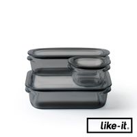 三個帶有密封蓋的透明玻璃保鮮盒，呈灰色調，大小各異，堆疊擺放。