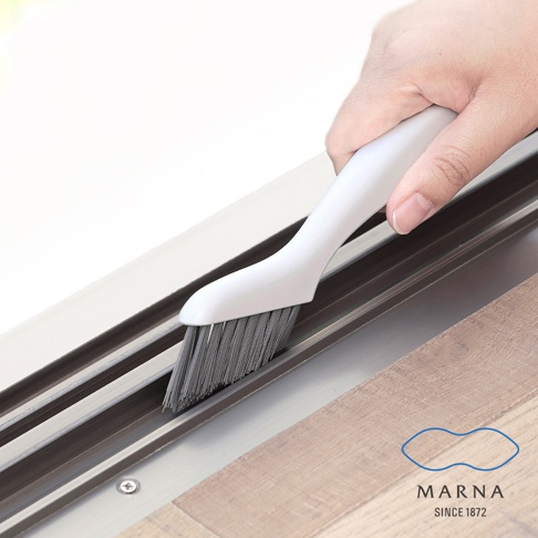 一隻手正拿著白色塑料手柄的縫隙清潔刷，刷毛為灰色，正在清潔鋁合金軌道。