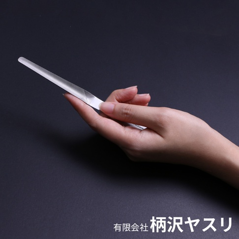 一隻手握持著細長、銀色的曲面高碳鋼銼刀，銼刀表面有細緻的紋理，背景為深色。
