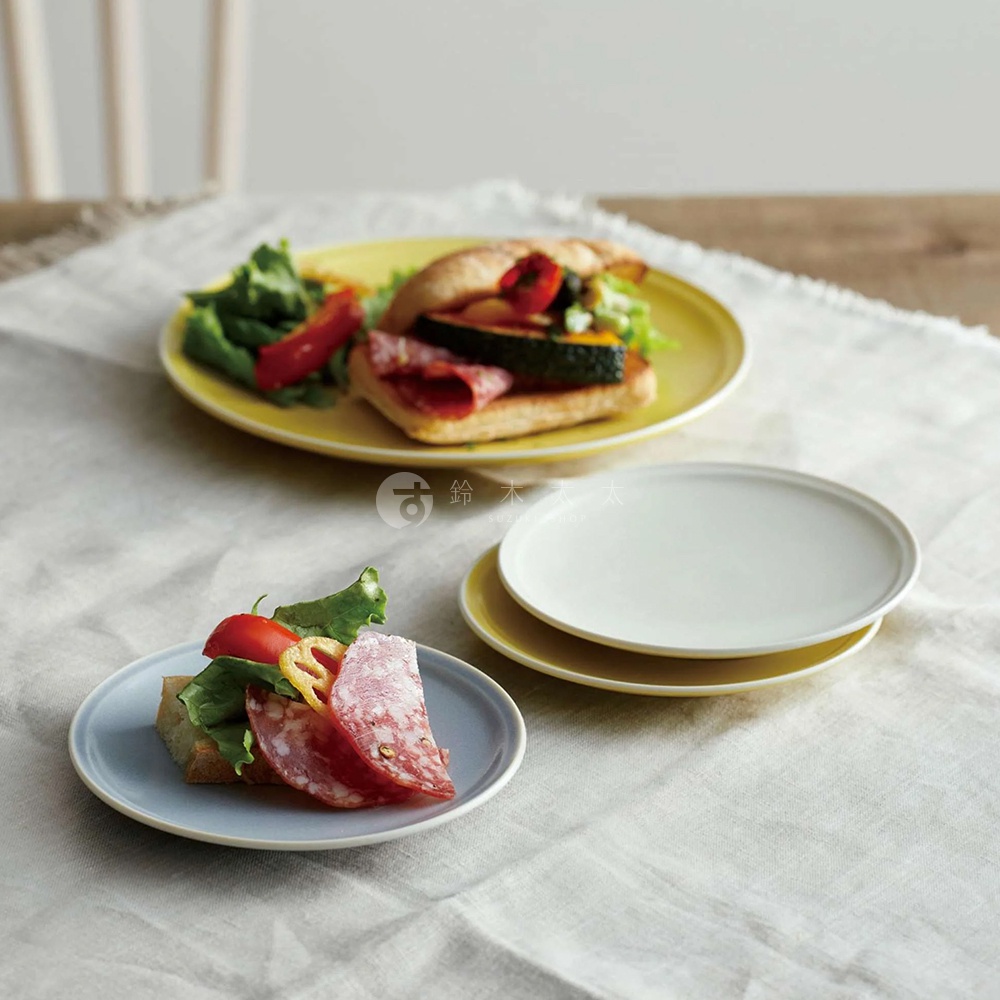 兩款美濃燒簡約素雅釉彩主菜盤，一款為淺藍色，盤中盛有三明治切片與沙拉；另一款為黃色，盤中盛有三明治與沙拉。另有疊放的白色與黃色盤子。