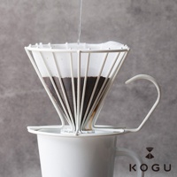 極簡白色鏤空線條日製18-8不鏽鋼咖啡濾杯，置於白色馬克杯上方，濾杯內有咖啡粉，上方正有水流下。