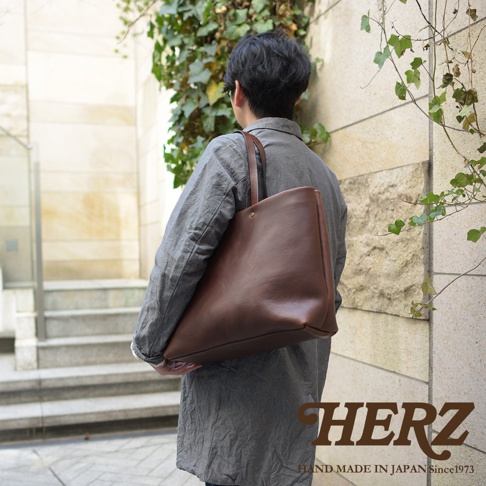 職人手作皮革4口袋極簡托特包T-3，展示為深棕色。此款托特包採用柔軟的皮革材質，設計簡約，具有寬敞的主隔層和四個內袋，肩帶為皮革材質，適合日常攜帶。