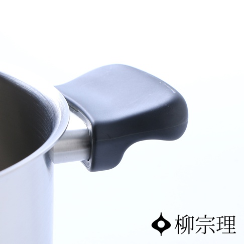 柳宗理不鏽鋼霧面雙耳鍋的局部特寫，畫面呈現鍋緣與黑色霧面質感把手的連接處，右下方印有柳宗理品牌名稱與標誌。