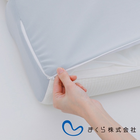 淺灰色網眼布材質的15度半身枕，側邊有白色拉鍊，一隻手正在拉開拉鍊，露出枕頭內部。