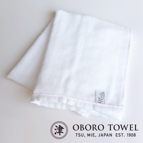 白色三層紗專身潔膚巾，織紋細緻，材質柔軟，一角有品牌商標與可愛的嬰兒圖案標籤。