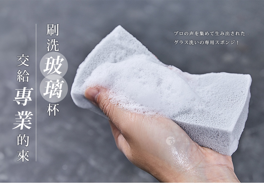 手持一塊淺灰色、帶有細緻氣孔的耐用海綿刷，海綿表面充滿白色泡沫，用於清潔玻璃杯。