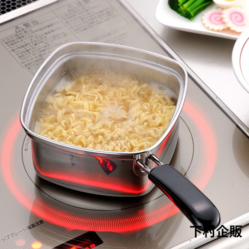 不鏽鋼方形單手麵鍋內煮著滾燙的麵條，鍋身呈現金屬光澤，鍋柄為黑色。鍋底下方有紅色的加熱指示。