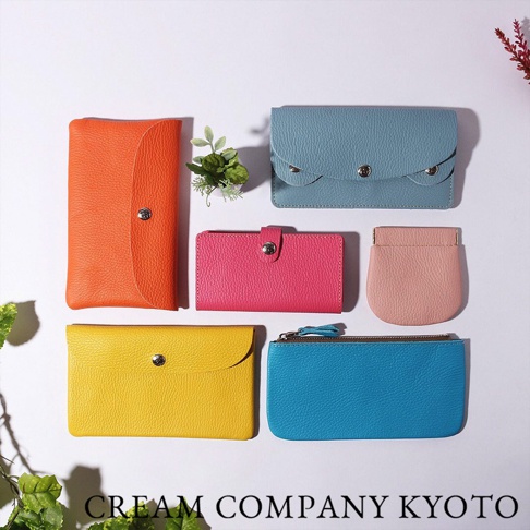 展示五款不同顏色（橘色、藍色、粉紅色、黃色、淺粉色）的皮革收納包，包含長夾、短夾、零錢包和化妝包。
