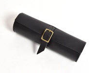 職人手作皮革捲捲收納筆袋，黑色皮革製成，帶有黃銅色帶扣和皮帶，用於固定捲起的筆袋。