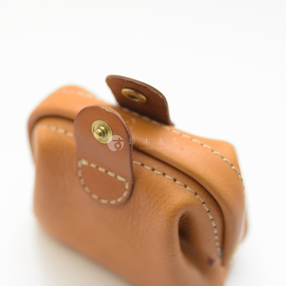 職人手作皮革口金化妝包，採用淺棕色皮革，配有金色金屬釦和縫線，造型簡潔。