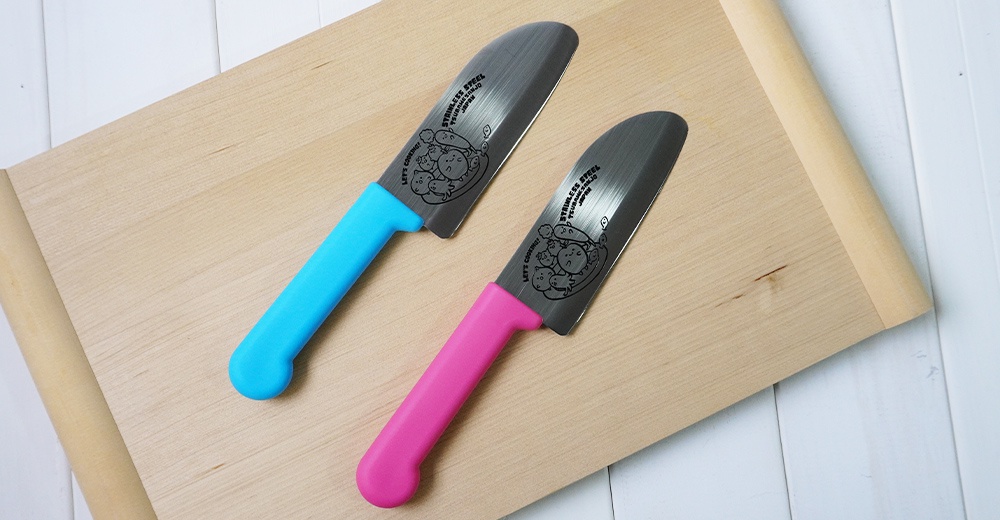 兩把燕三條不鏽鋼兒童學習刀，一把藍色刀柄，一把粉紅色刀柄，刀片上印有可愛圖案和日文文字。