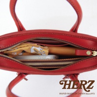 紅色皮革手提包，內部裝有手機、錢包和黃色印花布料。