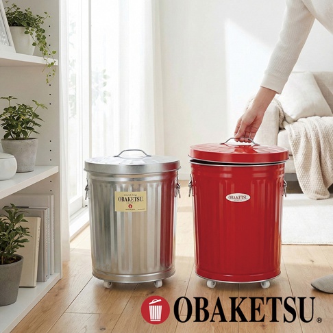 OBAKETSU 經典紅色和銀色附輪垃圾桶，擺放在室內木地板上，其中銀色垃圾桶標籤顯示「OBAKETSU」和「MADE IN JAPAN」。